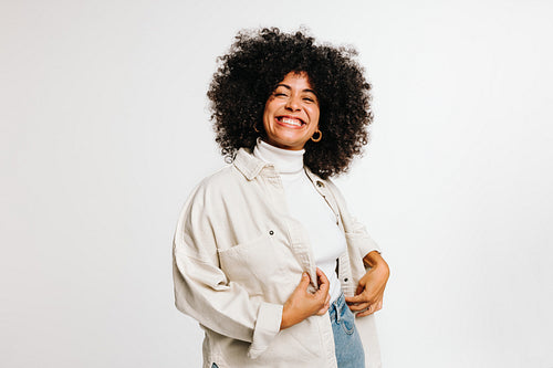 Happy woman with curly hair smiling at the camera in a studio