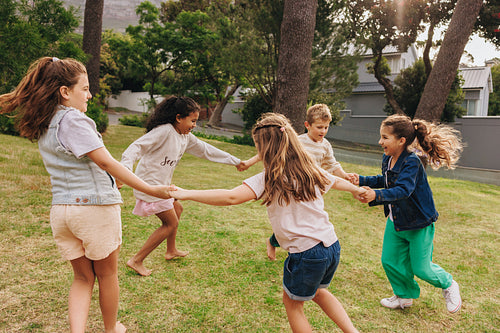 Children playing together in a grassy park during a sunny day