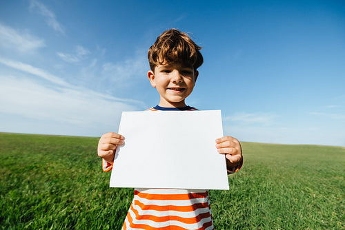 Boy holding blank sign in open field