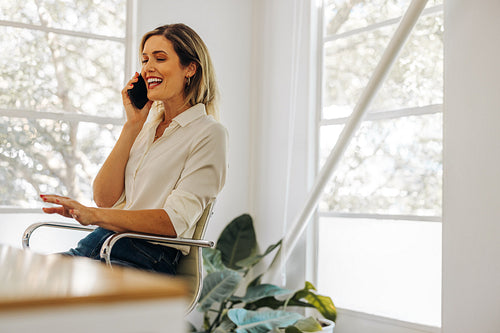 Happy businesswoman taking a phone call in her home office