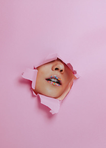 Woman with creative lips makeup through torn paper