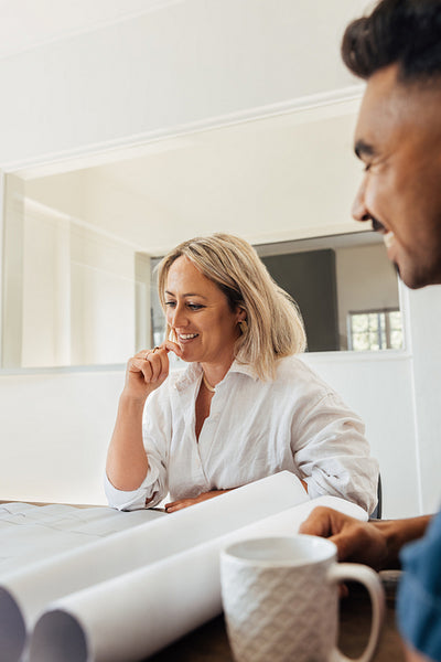 Two architects discussing project plans over coffee in a contemporary office setting