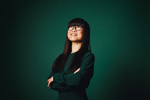 In the studio, the woman offers a smiling business portrait with glasses