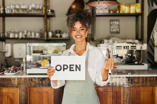 Mature businesswoman holding an open sign at her new cafe