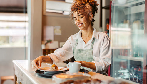 Cheerful female barista serving an order in a cafe