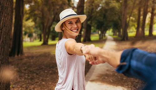 Romantic woman leading a walk with her partner in park