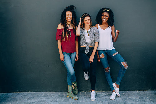 Friends posing for photograph standing against a wall