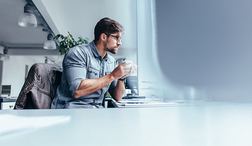 Businessman sitting in office with cup of coffee