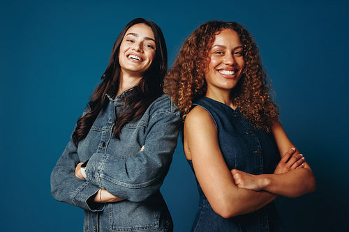 Best friends share a smiling studio portrait with crossed arms and confidence