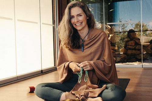 Mature woman meditating with a beads necklace at home