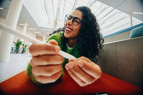Cheerful woman holding pen in an indoor setting with tablet POV