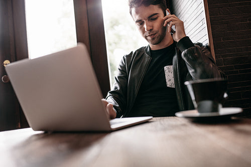 Young man talking on cell phone at cafe