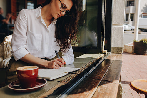 Woman taking notes in the cafe
