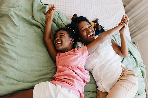 Mother and daughter enjoy bonding time, laughing and having fun together on the bed