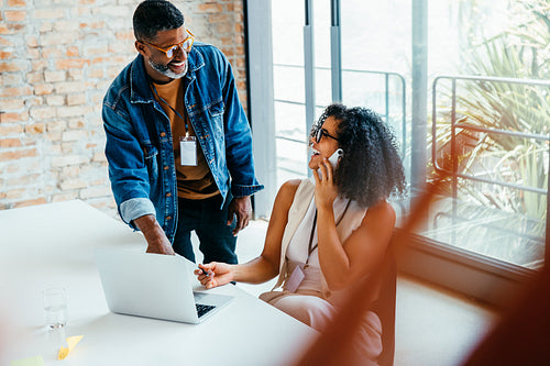 Colleagues engaged in a dynamic phone conversation at a bright modern office, sharing ideas for a successful project outcome