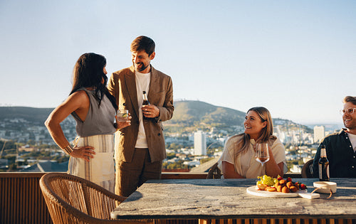 Friends enjoying conversation and drinks on a rooftop during a beautiful evening