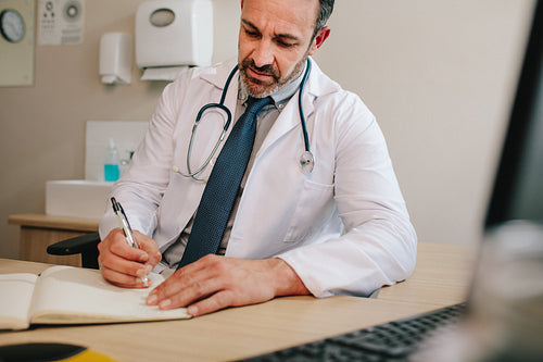 Doctor writing notes on patient in office