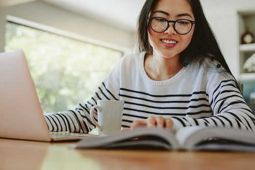 Smiling young woman studying at home