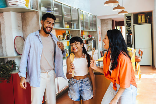 Playful Latin American family laughing together in a vibrant kitchen setting