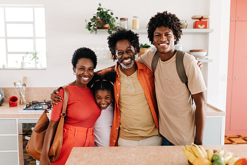 Portrait of a happy black family standing together in the kitchen after their daily routine