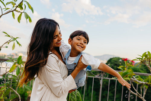 Mother holding her smiling son outdoors on a beautiful sunny day