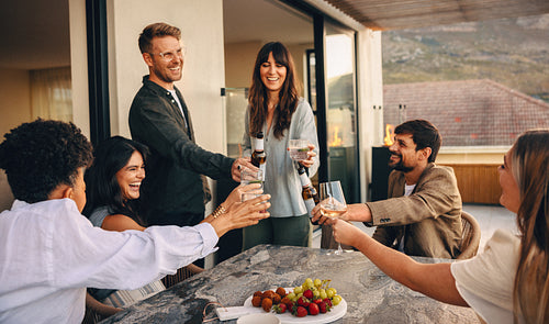 Friends toasting with drinks on a terrace during a friendly evening event