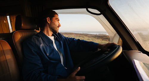 A man drives a van with calm focus as the road stretches toward the horizon