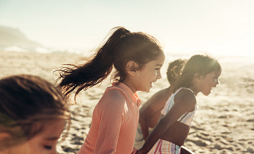 Group of energetic kids running together at the beach