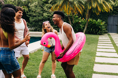 Friends gather by pool with pink flamingo float