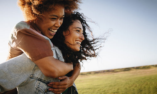Joyful friends enjoying a playful moment together outdoors, embracing and laughing