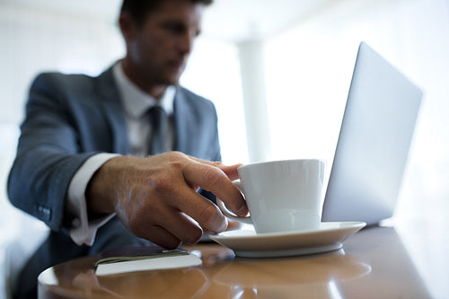 Businessman in office lobby picking cup of coffee