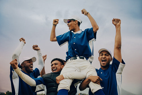 Joyful baseball team celebrating victory with players lifting a teammate in triumph