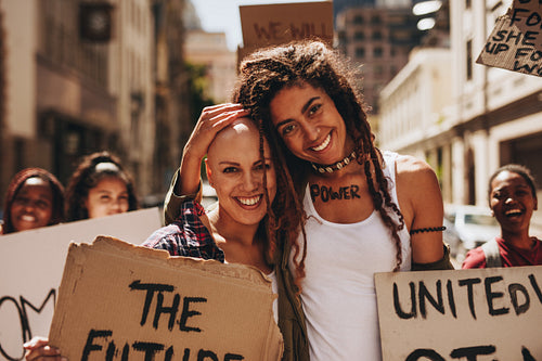 Happy women with placards protesting outdoors