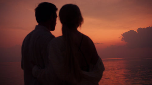 Romantic couple embracing by the ocean at a beautiful tropical sunset