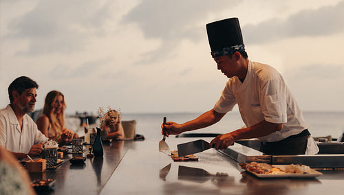 Outdoor teppanyaki dining experience with a chef preparing food at sunset