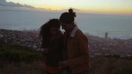 Loving young couple on cliff at sunset