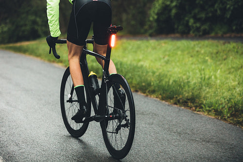 Male cyclist practising on a wet road