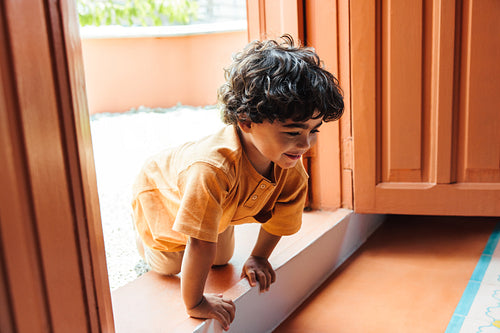 Curious young boy exploring the outdoors while playing near a colorful home