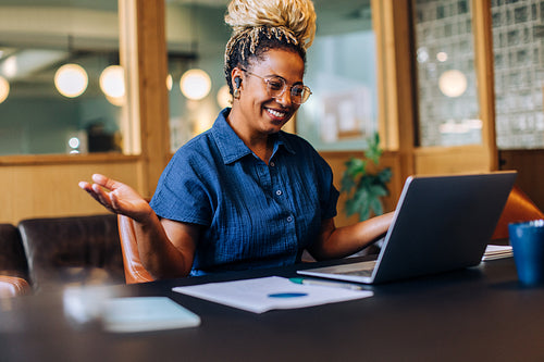 Happy woman at work using a laptop in an office environment