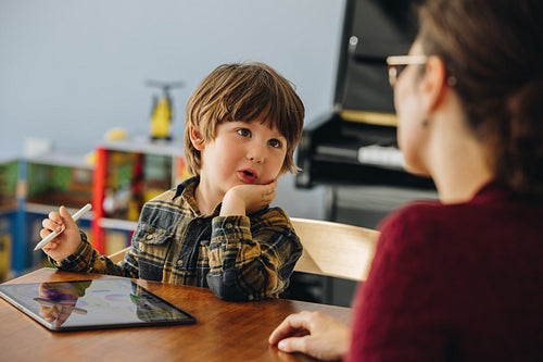 Cute boy talking with mom while using digital tablet