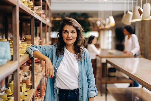 Confident young woman looking at the camera in her ceramic store