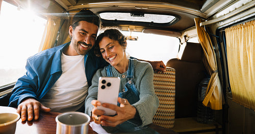 Couple enjoying a road trip in a cozy camper van taking a selfie
