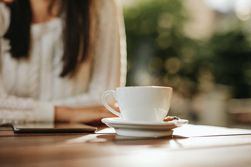 Cup of coffee and digital tablet on cafe table with woman.