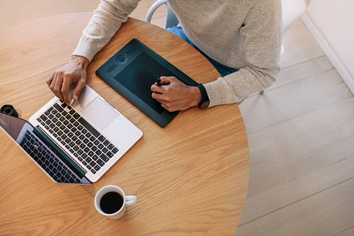 Businessman working on laptop computer using a digital writing pad