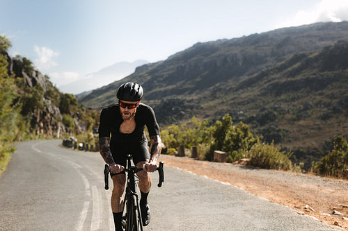 Sportsman riding bicycle on curvy mountain road