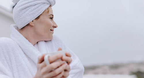 Woman looking outdoors holding a coffee cup