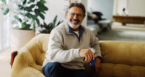 Senior man holds a credit card while shopping online at home