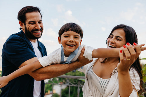 Happy parents playing with their young son on a sunny day outdoors