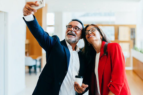 Smiling colleagues take a selfie together while enjoying a break in the office