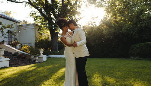 Wedding couple dancing in a scenic outdoor garden during golden hour